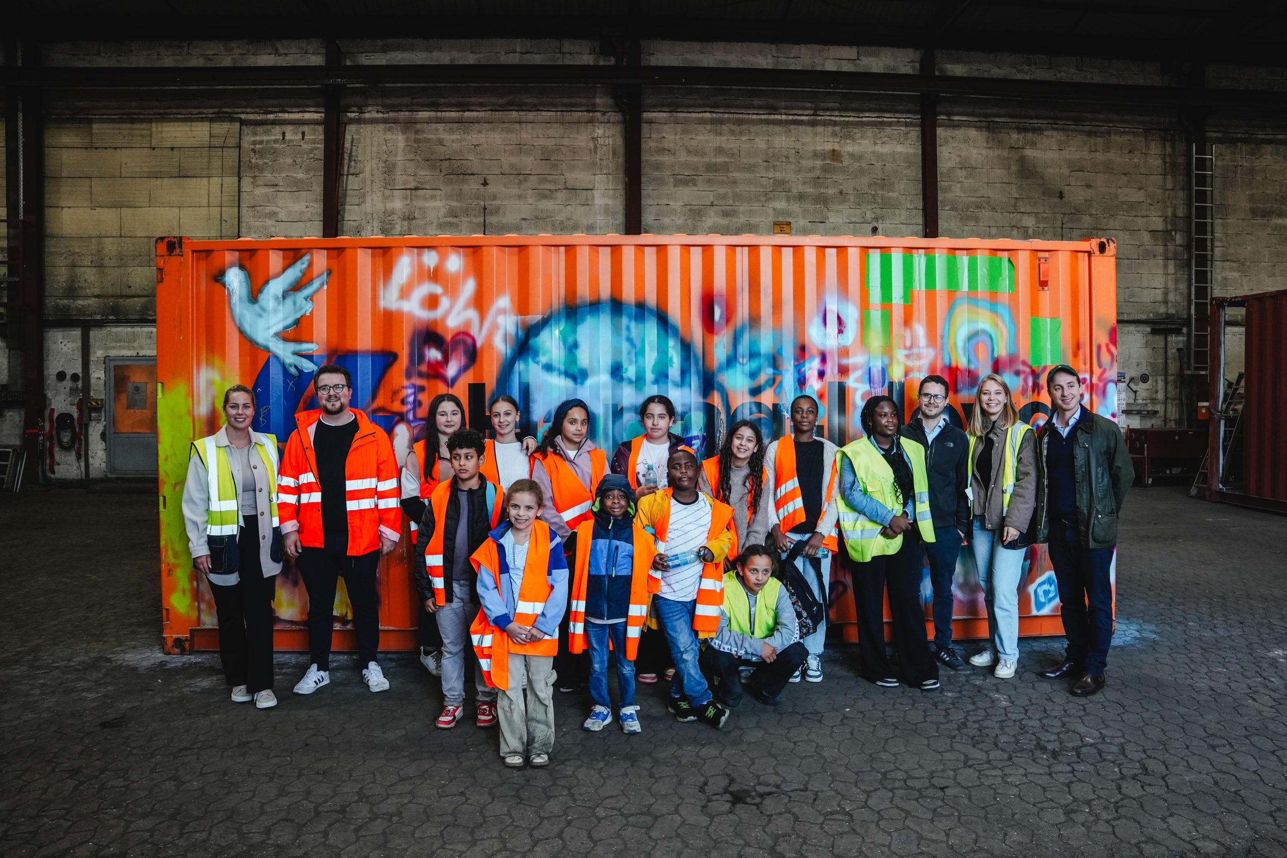 Gruppenbild mit einer Kindergruppe und Mitarbeitern der Hapag-Lloyd vor einem bemalten Container