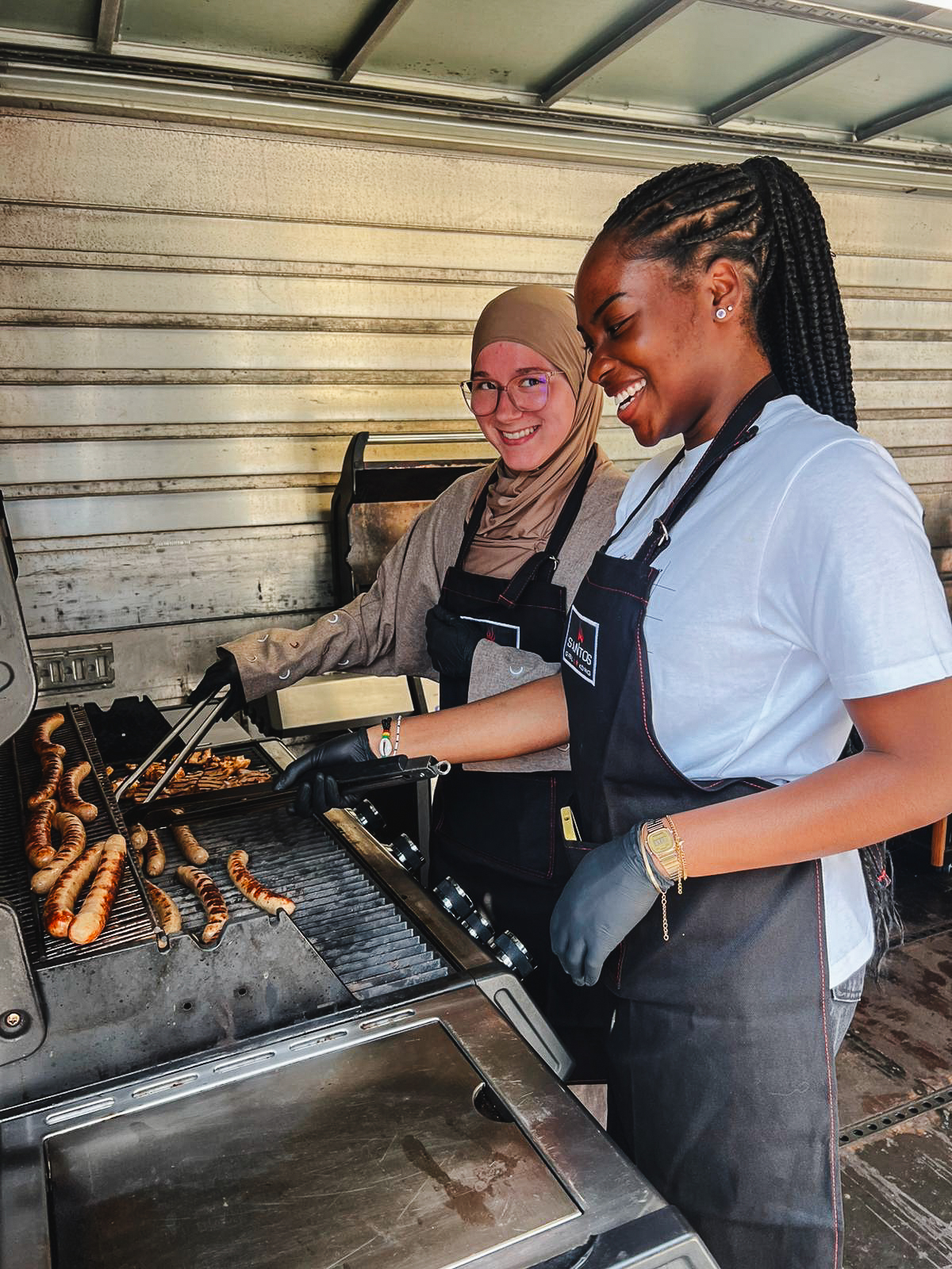 Zwei Jugendliche grillen Fleisch auf einem Gasgrill