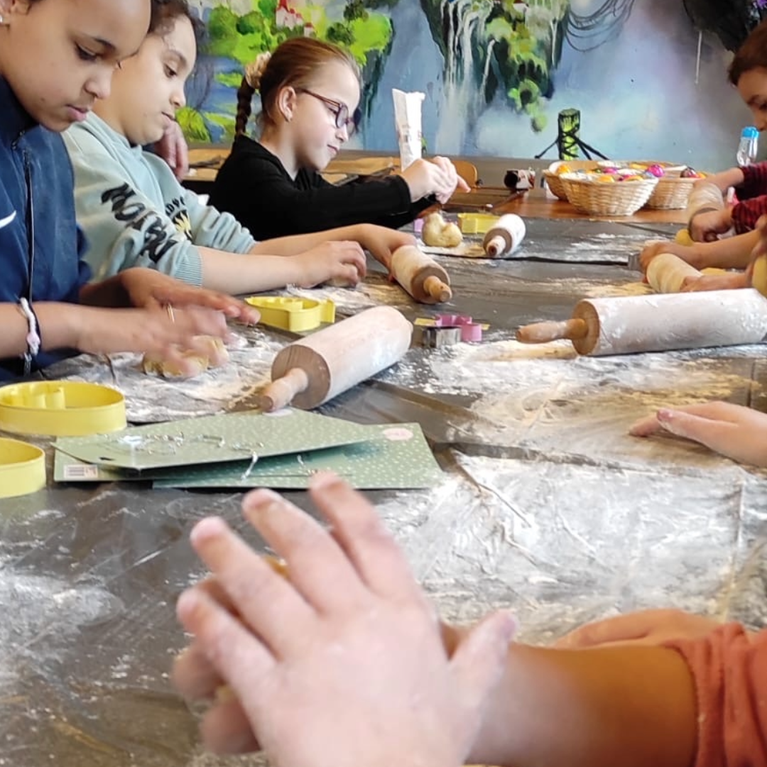 Kinder und Erwachsene beim Keksebacken, mit Teig und Ausstechformen auf einem Tisch.