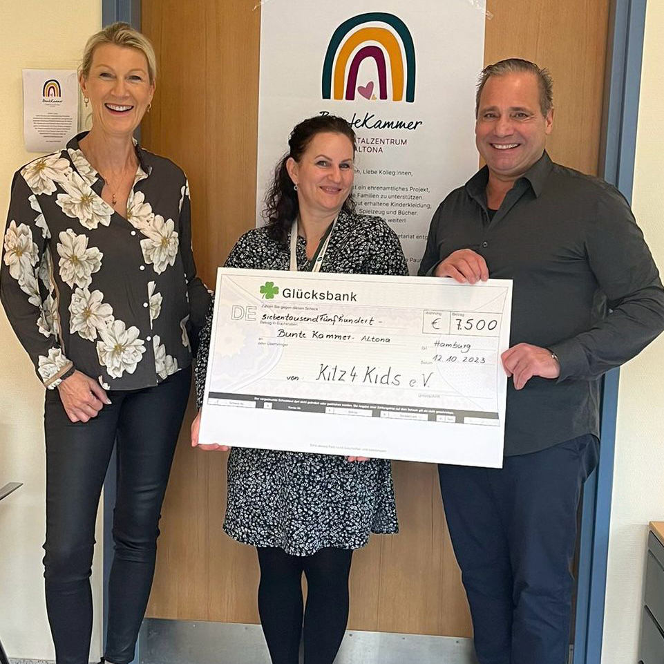 Zwei Frauen und ein Mann präsentieren einen großen Scheck.