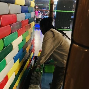 Kinder spielen mit Bausteinen an einer gemusterten Wand.